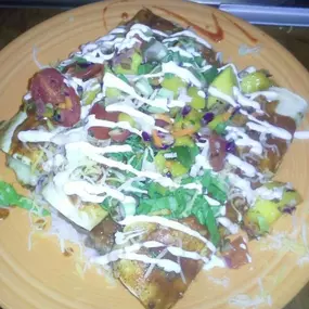 Seafood Enchiladas topped with a tequila enchilada sauce, lime sour cream and mango salsa.