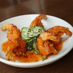 Crispy colossal shrimp, firecracker sauce, sesame, and cilantro cucumber salad.