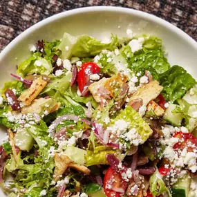 Greek salad with mixed field greens, cucumbers, grape tomatoes, red onions, olives, feta, seasoned pita crisps, and Greek dressing.