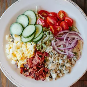 Cobb Salad with romaine, grape tomatoes, cucumbers, red onions, applewood smoked bacon, blue cheese crumbles, hard boiled egg, and black pepper ranch dressing.