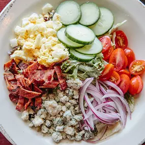 Cobb Salad with romaine, grape tomatoes, cucumbers, red onions, applewood smoked bacon, blue cheese crumbles, hard boiled egg, and black pepper ranch dressing.