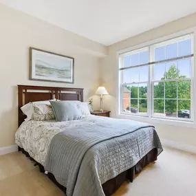 A bedroom with a large window and carpet flooring at Claremont Apartments.