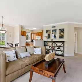 A living room with open access to a dining area and kitchen near a large window at Claremont Apartments.