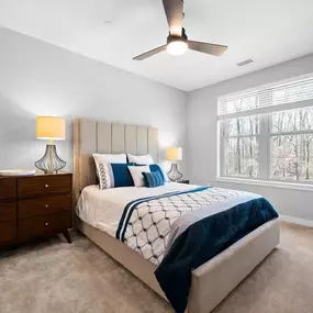 A bedroom with a large window, carpet flooring, and a ceiling fan at Hamilton at Eagleview.