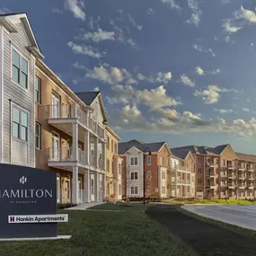 The exterior view of Hamilton at Eagleview's 3-story apartment building with a property sign and grass.