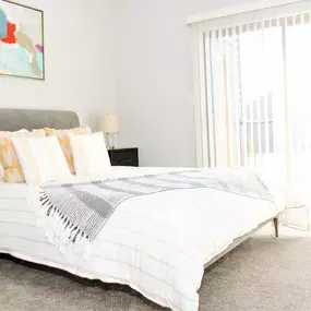 A bedroom with carpet flooring and a large sliding door to a patio at Sugar Creek Apartments.