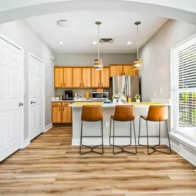 A kitchen with hardwood-style flooring, a breakfast bar and a large window at The Legends on the Park.