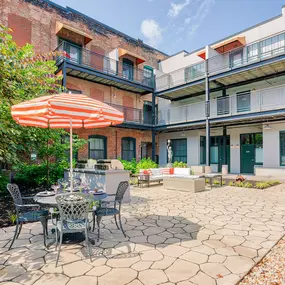 An outdoor courtyard with a chair and an umbrella surrounded by apartments at Wireworks Lofts in the Square.