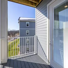 A view from a balcony looking out at a house and a field.