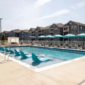 A large swimming pool with lounge chairs and umbrellas.