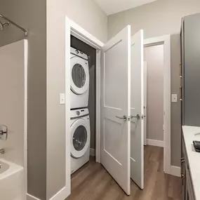 A bathroom with a washer and dryer in the doorway.