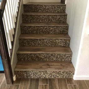 Elevate your home with expert tile stairs installation by Straight Edge Flooring, your trusted flooring company. This stunning staircase combines wood-look steps with intricate mosaic risers, adding both beauty and durability to your space. Visit our showroom today for high-quality flooring solutions tailored to your style!