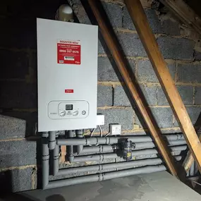 Newly installed white Main boiler in an attic space with insulated piping.