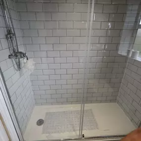 Walk-in shower with white subway tiles, chrome fixtures, and a clear glass door.