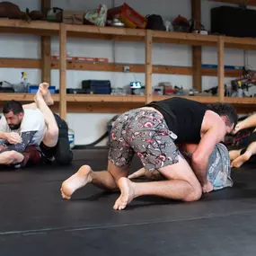 Some people rolling/jiu jitsu sparring at a Sunday Open Mat