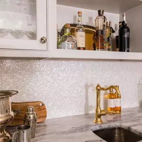 A modern kitchen with white cabinetry, highlighted by a sparkling backsplash of Mother of Pearl tiles.