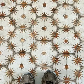 A decorative tile pattern featuring golden starbursts on a cream background.