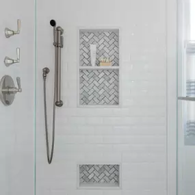 A bright shower space featuring a white subway tile design and elegant niche details. Beveled 3x6 with marble mosaics.