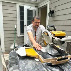 A tile installer using a wet saw to cut tiles on a job site, focused on precision.