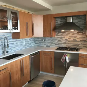 A contemporary kitchen featuring wooden cabinets and a blue glass mosaic tile backsplash.