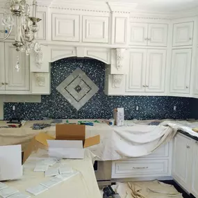 A luxurious kitchen under renovation, with a decorative blue backsplash as the central feature.