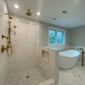 A luxurious bathroom featuring a freestanding tub, gold fixtures, and a decorative shower niche.