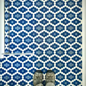 An intricate pattern of blue and white mosaic tiles forming a bold, eye-catching feature shower floor with linear drain. The short metal rail is for glass to be installed on top of it. Tiles by American Restoration Tiles