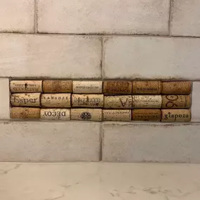 A close-up of a kitchen backsplash featuring unique textured tiles made of actual vintage wine corks.