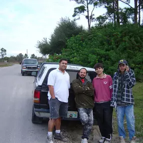 A group of four workers taking a break next to their vehicles on a roadside, enjoying camaraderie.