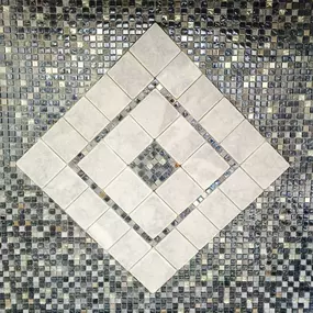 A decorative tile accent featuring a diamond pattern with a mix of mosaic and large tiles.