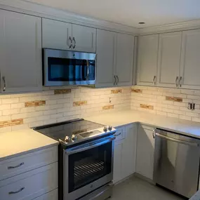 A cozy kitchen illuminated by soft lighting, showcasing a beige rustic subway tile with wine corks custom made tiles deco on backsplash and stainless steel appliances.