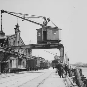 Eine historische Aufnahme des Oldenburger Hafens mit einem imposanten Hafenkran und Lagergebäuden. Dieses Bild zeigt die industrielle Vergangenheit der Stadt und die Verbindung zum wirtschaftlichen Zentrum.