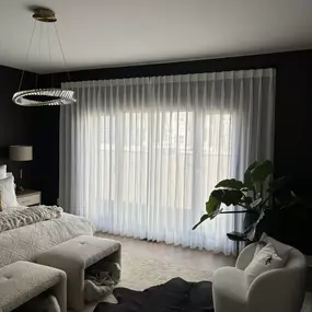 White sheer drapes with French returns provide an airy and elegant feel to a dark green wall.