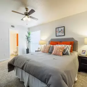 Spacious master bedroom featuring plush carpet flooring, a ceiling fan, and abundant natural light. Includes a private en-suite bathroom, large walk-in closet, and stylish décor with neutral tones and accent pillows for a warm, inviting atmosphere.
