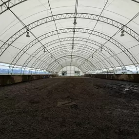 Wide interior view of a large Pilot Buildings arched fabric structure used as a riding hall (arena), showing the expansive footing area.