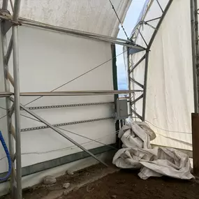 Close-up interior view showing structural details and utility installation near the base of a Pilot Buildings arched structure.