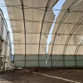 Interior view of a Pilot Buildings arched structure, likely an arena, showing the roof fabric cover with significant gaps or tears near the peak.