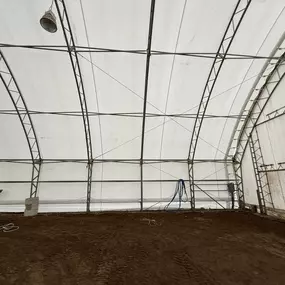 Interior view focusing on the base of the end wall and side wall within a Pilot Buildings arched structure, showing framing and floor details.