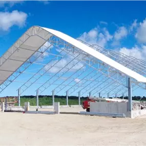 A Pilot Buildings structure with straight side posts and an arched roof, shown during construction with the steel frame erected and roof fabric partially installed.
