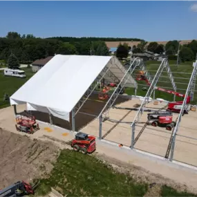 High-angle view of a Pilot Buildings structure under construction, showing the steel frame on concrete walls with the roof cover partially installed and various pieces of equipment on site.