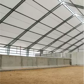 Interior view along the side of a Pilot Buildings straight-wall structure, configured as a riding arena with a concrete kick wall.