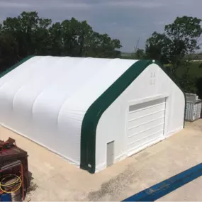Elevated exterior view of a completed Pilot Buildings structure with a white fabric cover accented by dark green trim on the end arches and corners.