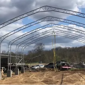 Partially erected steel frame of a Pilot Buildings structure featuring straight leg posts and a peaked roof profile, mounted on concrete block foundations during construction.