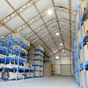 Interior of a Pilot Buildings arched fabric structure functioning as a warehouse, filled with tall industrial racking systems storing bundled materials.