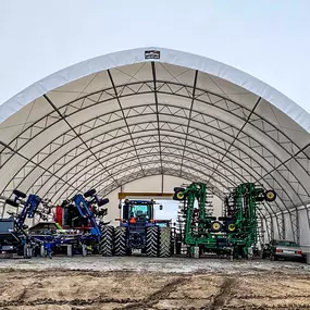 Front view into a large, open-ended Pilot Buildings arched fabric structure used for storing multiple pieces of heavy farm machinery.