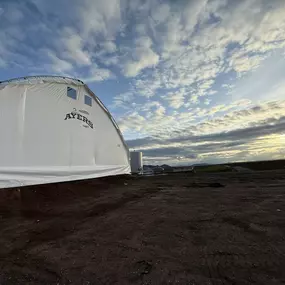 This image displays a finished, custom-branded fabric-covered building designed by Pilot Buildings. The durable, white fabric exterior is tensioned over a sturdy frame, showcasing a practical and bright solution for agricultural or commercial storage. The 