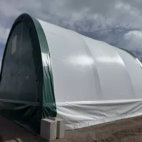 This image showcases a completed, durable fabric-covered building from Pilot Buildings. Featuring a two-tone design with a white cover and green endwalls, this structure offers a visually appealing and practical solution for storage, workshops, or agricultural use. The arched profile and tensioned fabric over a high-strength frame ensure resilience in various weather conditions. This building is a prime example of our versatile and cost-effective construction options.