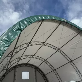 This close-up image highlights the superior construction and structural integrity of a Pilot Buildings fabric structure. The view looks up into the galvanized steel truss system, showcasing the robust engineering that provides clear-span space and durability. The dual-layer design, featuring a bright white interior liner and a heavy-duty green exterior cover, is clearly visible, demonstrating the quality materials used for weather protection and longevity.