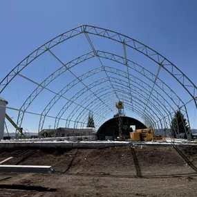 This head-on photo captures the impressive scale of a Pilot Buildings arch structure during the framing stage. Looking through the galvanized steel 