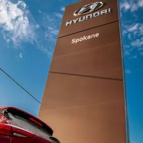 Rear view of a Hyundai Tuscon parked in front of the Spokane Hyundai dealership sign